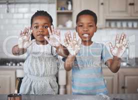 Dirty hands, pure hearts. Shot of a little girl and boy having fun while baking together at home.