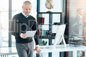 I pay attention to customer feedback to better my company. Shot of a mature businessman using his digital tablet at the office.