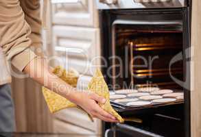 In 30 minutes Ill have cups of yumminess. Shot of a woman inserting a tray of cupcakes into the oven to bake.