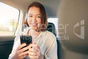 When life gives you wheels go see the world. Shot of a young woman using a smartphone while traveling in a car.