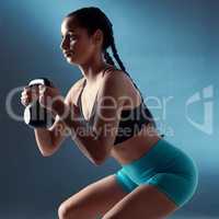 Dont let your excuses weigh you down. Studio shot of a sporty young woman doing kettlebell squats against a blue background.