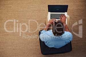 What the weekend is all about. High angle shot of a young man using his laptop while sitting at home.