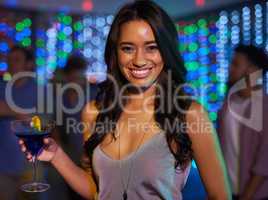 I love the vibe at this place. Portrait of an attractive young woman having a drink while partying in a club.