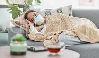 If youre feeling ill, stay home. Shot of a woman wearing a mask while lying sick at home.
