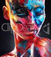 Living boldly. Shot of an attractive young woman posing alone in the studio with paint on her face.