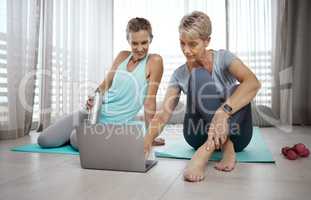 Better sore than sorry. Shot of two mature women browsing the internet for new workout ideas while exercising at home.