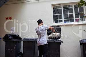 Doing the responsible thing. Shot of a young man putting newspaper in the bin to be recycled.