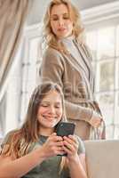 Sometimes space is necessary. Shot of a mature mother sneakily checking what her daughters doing on her phone at home.