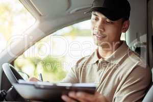 Making sure that all of my info is correct. Shot of a delivery man checking the paperwork for his delivery in his car.