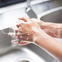 I wash my hands the minute I enter the house. Cropped shot of an unrecognizable woman washing her hands in the sink at home.