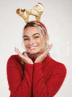 Christmas magic is silent. Studio shot of a young woman wearing a reindeer headwear and posing against a grey background.