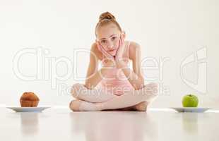 You hurt by starving yourself. Shot of a young ballerina deciding what to eat in a studio.