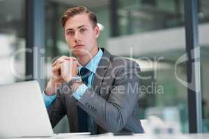 I have big plans for my career. Cropped portrait of a handsome young businessman sitting alone in his office and looking contemplative while using his laptop.