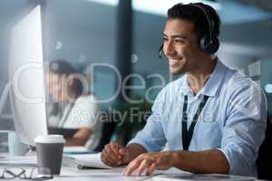 Where would we be without loyal customers like you. Shot of a young man using a headset and computer in a modern office.