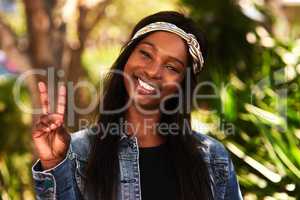 Peace out world. Portrait of an attractive young woman making the peace sign while relaxing in a park outdoors.