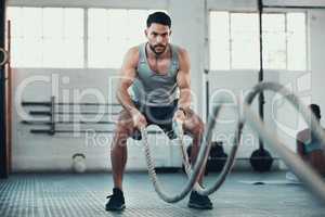 Never give up never surrender. Shot of a young man using the ropes in the gym to build arm strength.