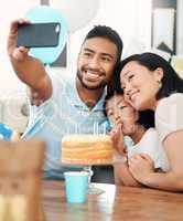 Work hard. Play hard. Eat lots of cake. Shot of a happy family taking selfies while celebrating a birthday at home.