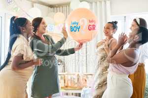 Time to find out. Shot of a group of women about to pop a balloon for a gender reveal during a baby shower.