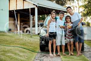 Families should always work together. Portrait of a group of young kids standing together and about to wash their parents car outside during the day.