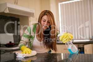 Keeping things clean. Shot of a young woman cleaning a kitchen countertop.