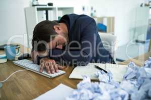 Drowning in paperwork. Shot of a stressed out businessman passed out at his desk overwhelmed by paperwork.