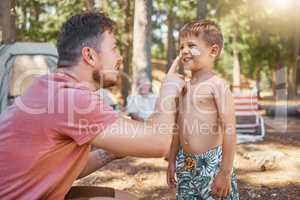 Dont forget your sunscreen. Cropped shot of a handsome young man putting sunblock on his adorable little son while camping in the woods.