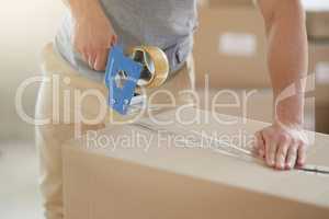 Sealed and secured. Shot of an unidentifiable young man closing a cardboard box with tape at home.