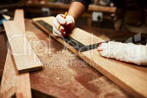 This will be more than we need. Closeup of an unrecognizable male carpenter doing measurements on a piece of wood inside of a workshop at night.