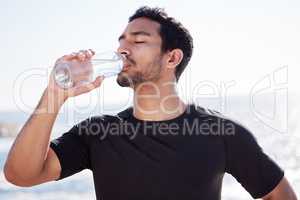 Stay hydrated. Cropped shot of a handsome young male athlete hydrating during his workout on the beach.