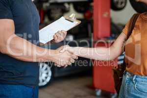 We offer great service and advice. Shot of a woman shaking hands with a mechanic in an auto repair shop.