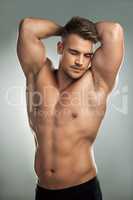 A bodybuilder is a sculptor who carries his own chisel. Studio shot of a muscular young man posing against a grey background.