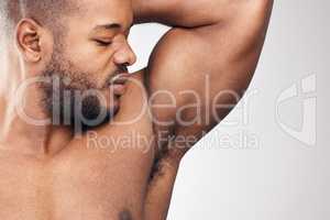 Whats that smelly smell. Studio shot of a handsome young man smelling his armpit against a white background.