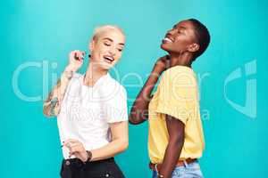 Good friends make for good times. Studio shot of two young women dancing together against a turquoise background.