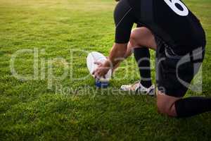 I need to score this. Cropped shot of an unrecognizable sportsman crouching alone during rugby practice in a sports club.