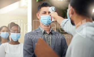 Lined up to be screened. Cropped shot of a handsome mature businessman wearing a mask and having his temperature taken while standing at the head of a queue in his office.