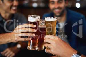 Well earned and ready to drink. Closeup of a group of young friends seated at a table together while enjoying a beer and celebrating with a celebratory toast inside a bar.