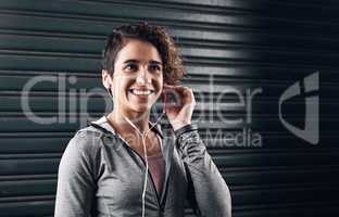 Time to blow off some steam. Shot of a young woman choosing the perfect song for her run outside against a black background.