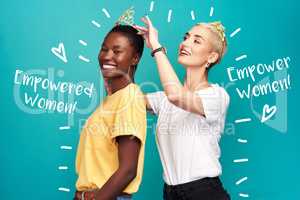 Not every queen needs a king. Studio shot of a young woman putting a crown on her friend against a turquoise background.