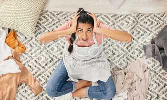 Someone save me from all these chores. Shot of a young woman sitting looking shocked while sitting in a messy living room at home.