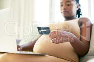 Paying for all the necessary items for the baby. Shot of a young mother to be using her bank card to make online payments.