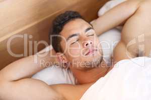 Take a few minutes for yourself in the morning. Shot of a handsome young man sleeping peacefully in bed.