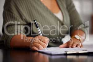 Lethal with a pen. Unrecognizable shot of a woman doing some paperwork at home.