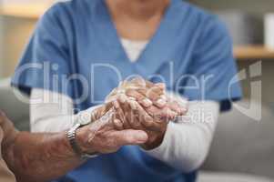 Heroes wear scrubs too. Shot of an unrecognizable nurse holding a patients hand during a checkup at home.
