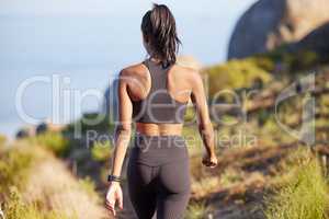Out for a day of toning. Rearview shot of a sporty young woman walking along a path outdoors.