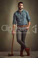 Dashing and daring. Studio shot of a young man posing with an axe against a green background.