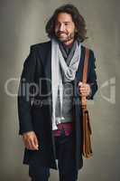 Men can dress up too. Shot of a stylishly dressed man posing with a leather satchel in the studio.