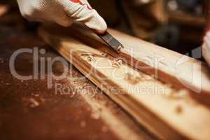 This tool works wonders. Closeup of an unrecognizable carpenter filing down a piece of wood inside of a workshop at night.