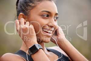 Lose yourself in your vibes. Shot of a young woman listening to music while jogging.
