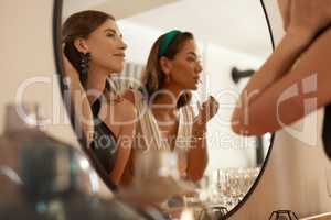 Got to keep the slay intact. Shot of two young friends standing together and using a mirror to touch up their makeup at a dinner party.