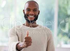 I approve. Shot of a young man showing a thumbs up at home.